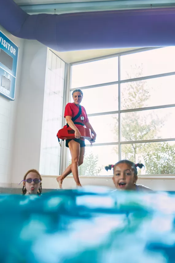 A lifeguard looking at a pool with two swimmers